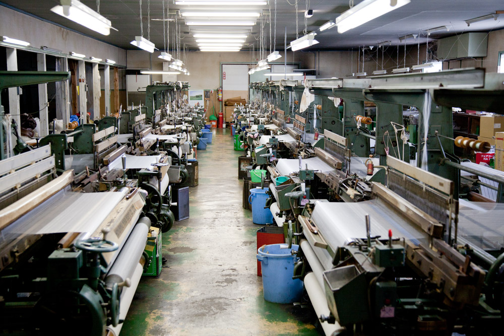 工場内部。数多に置かれた織機はどれも年期の入ったものばかりですが、ひとたび起動させるとガッシャンガッシャンと威勢良く機織りを始めます 